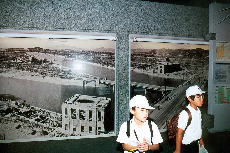 schoolboys turning away from a large photograph of the destroyed city