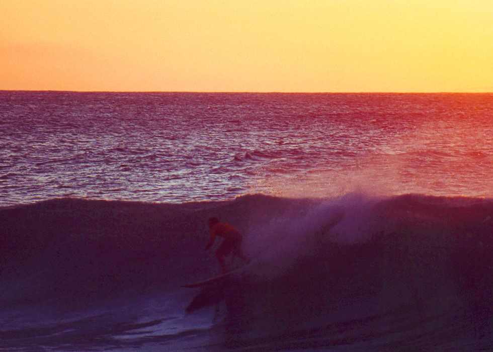 sunset engulfs a surfer