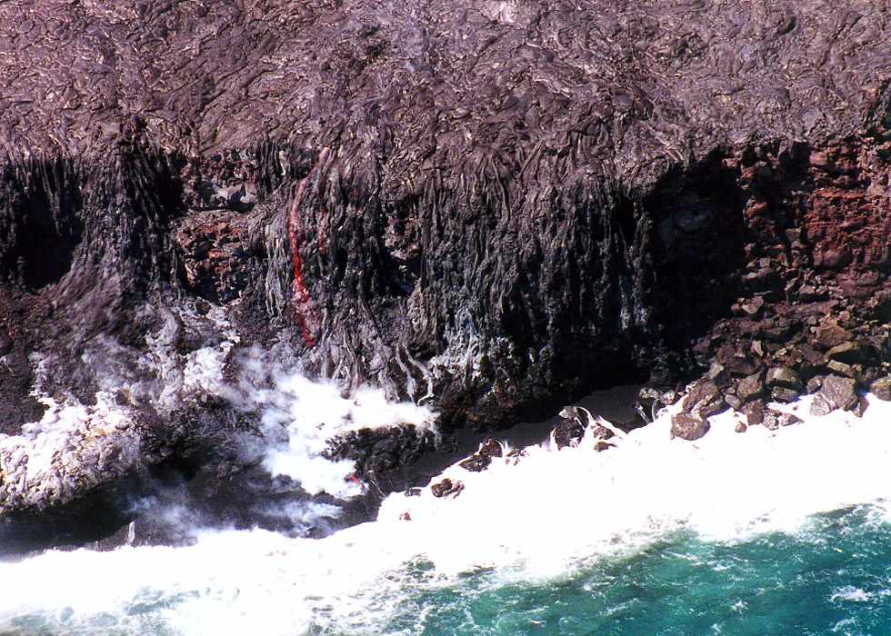 lava flowing down a wall and into the ocean