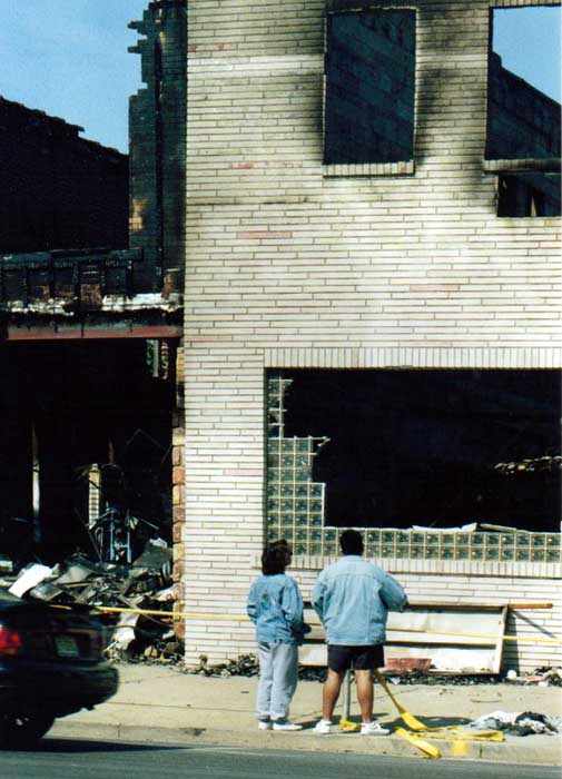 people standing in front of burned out stores on Main Street